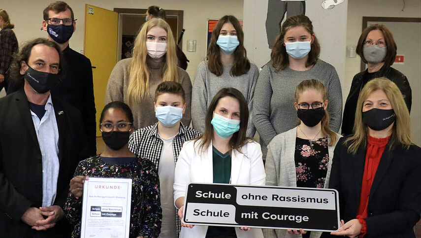 Gruppenfoto mit Maske mit 12 Personen zum Thema 'Schule ohne Rassismus - Schule mit Courage'