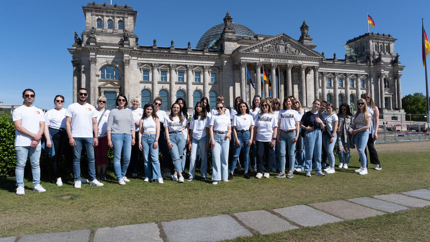 Eine große Personengruppe steht vor dem Reichstagsgebäude in Berlin